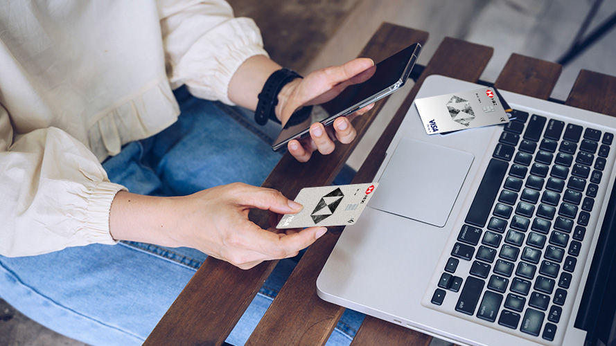 a man holding an HSBC card, and using his mobile for online shopping