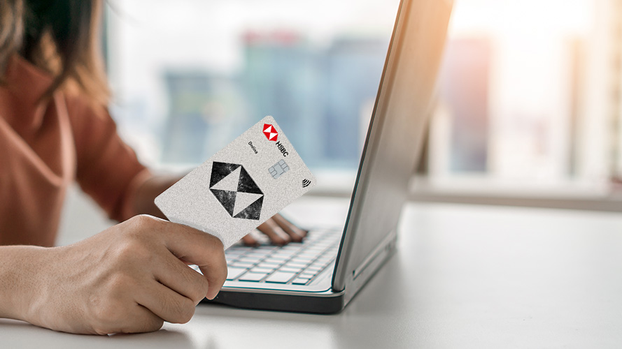 a woman handing over an HSBC card above a coffee table; image used for what is a visa card article page