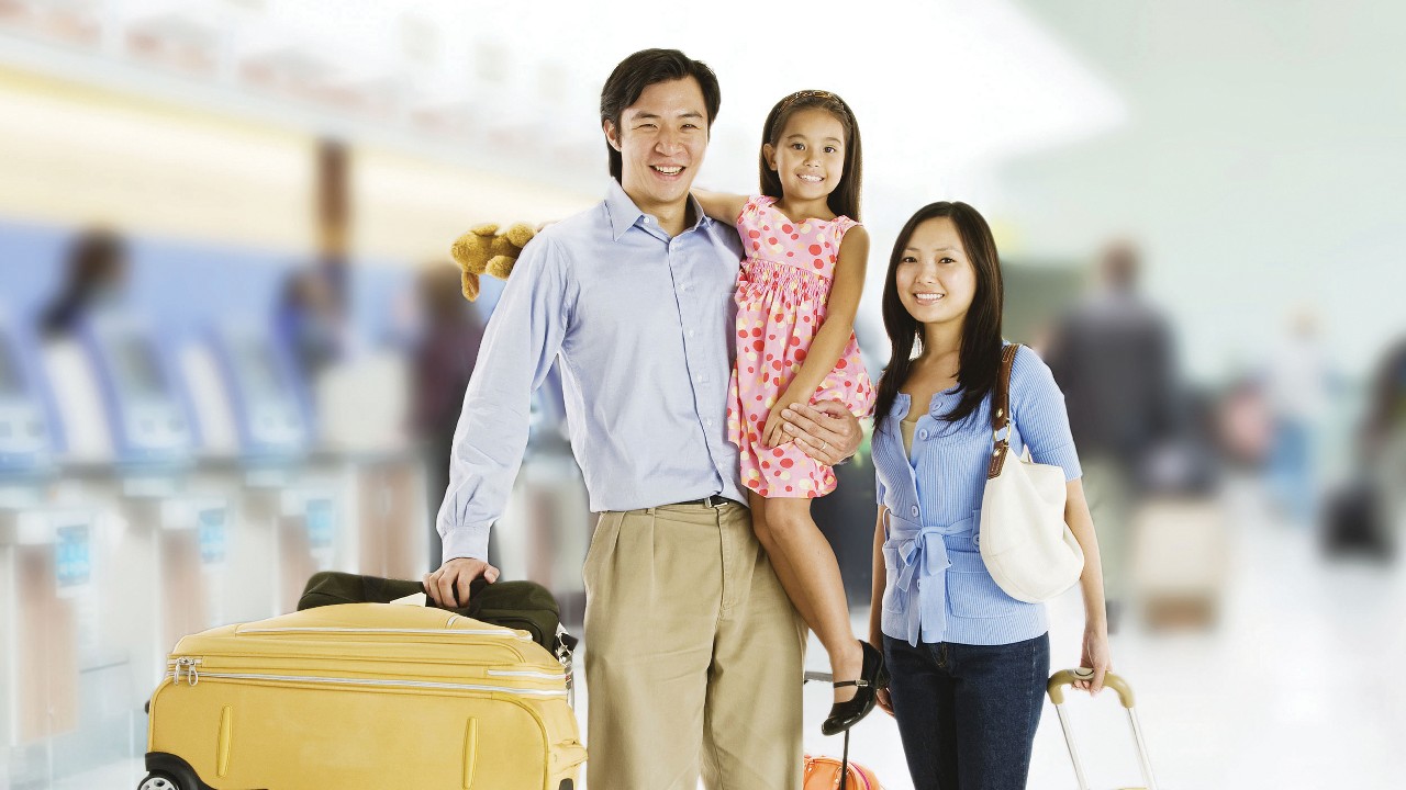 Family with luggage at airport; image used for HSBC Vietnam Travel Care Insurance page