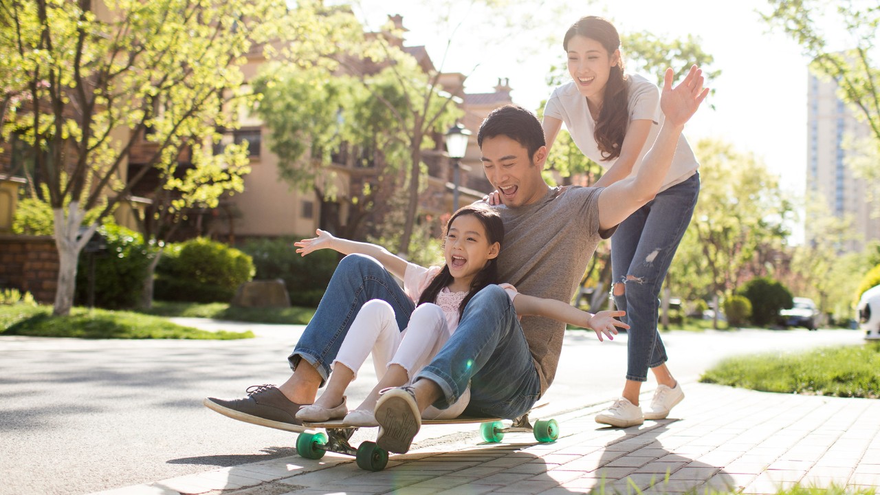 a happy family of three playing skateboard together; image used for HSBC Vietnam insurance page. 