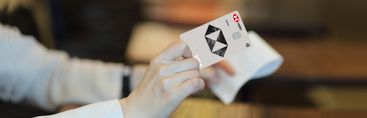 a woman handing over an HSBC card above a coffee table; image used for what is a visa card article page