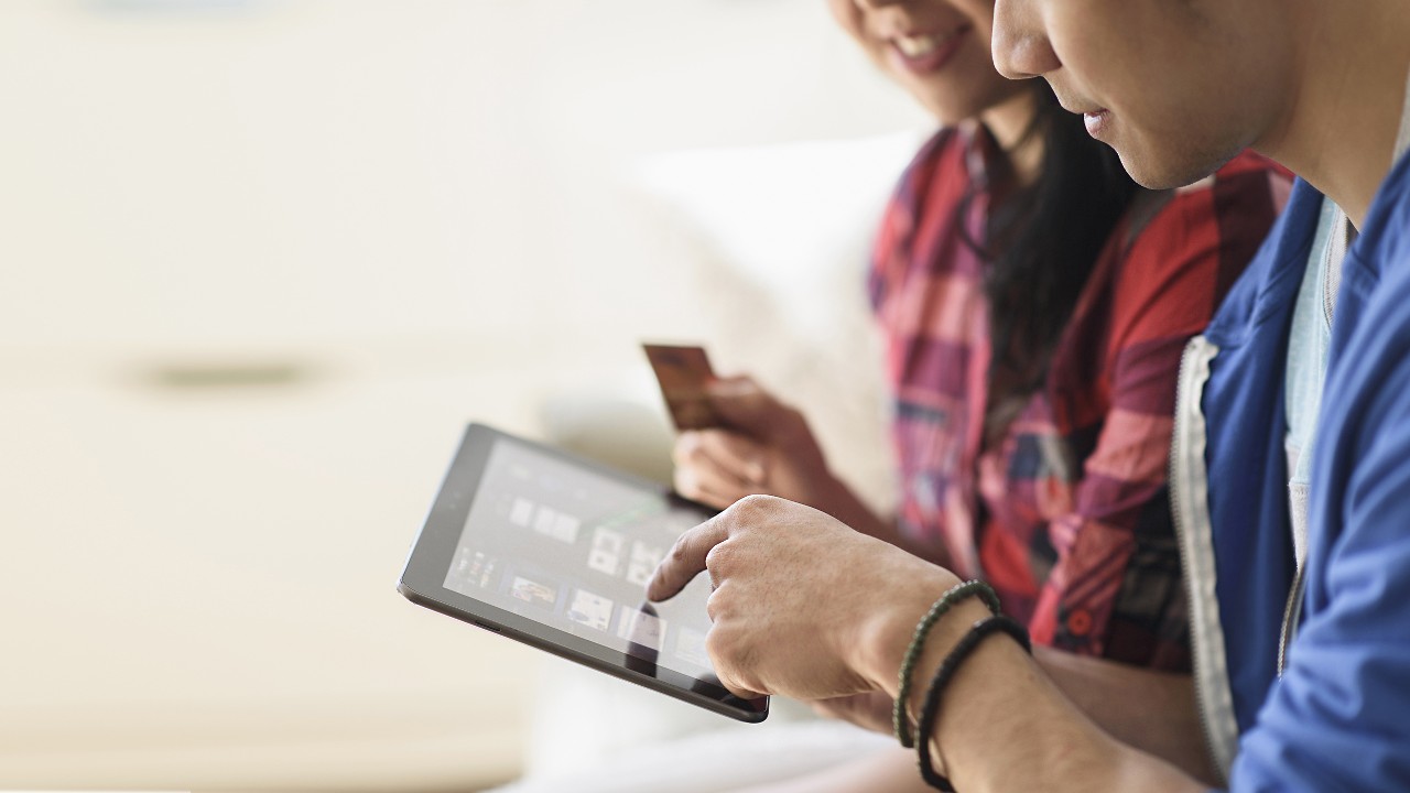 A young couple holding an iPad and a credit card; image used for HSBC Vietnam e-voucher reward page.