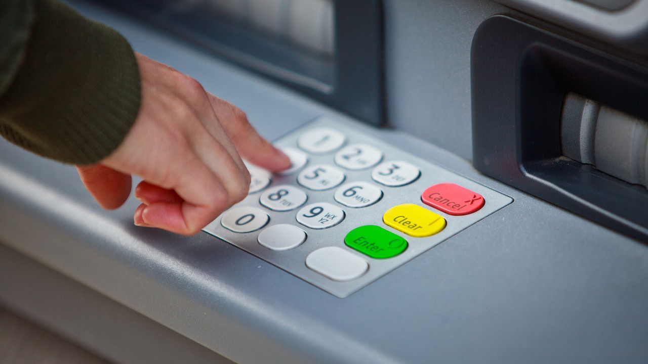 A person is keying the passcode on ATM keypad
