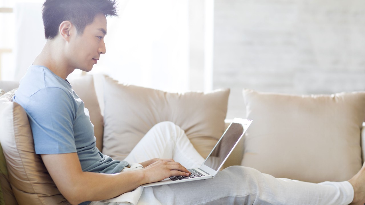 a young man sitting on a sofa using laptop