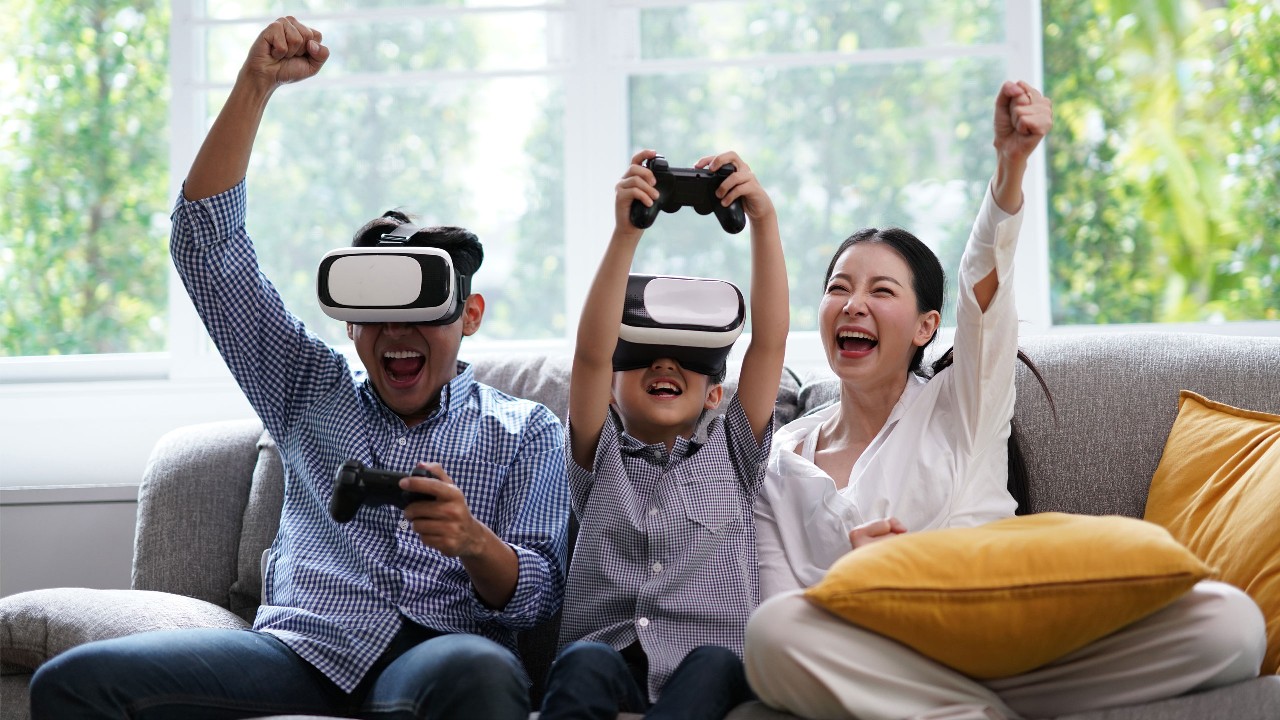a family of three playing VR games on a sofa