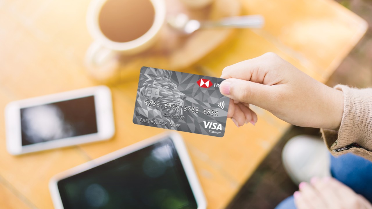 a woman handing over an HSBC card above a coffee table; image used for what is a visa card article page