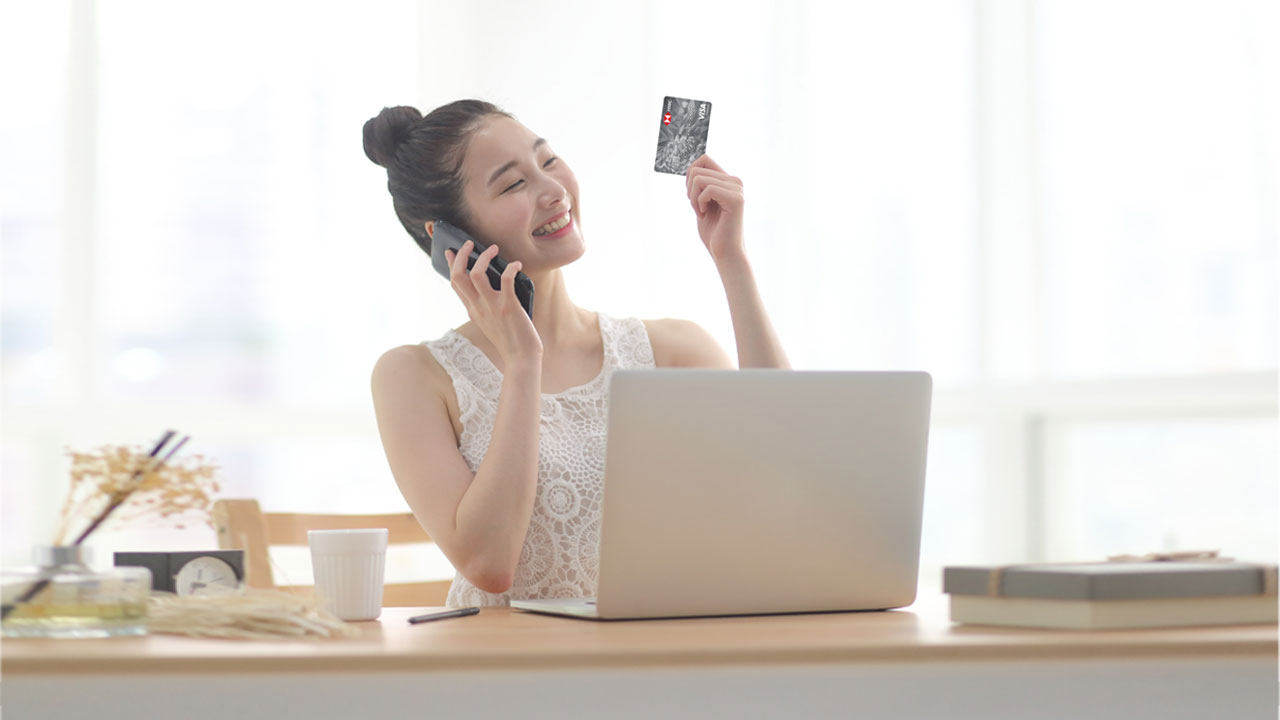 A woman is holding a credit card while talking on the phone; image used for HSBC VN How to get a 45-day interest-free period