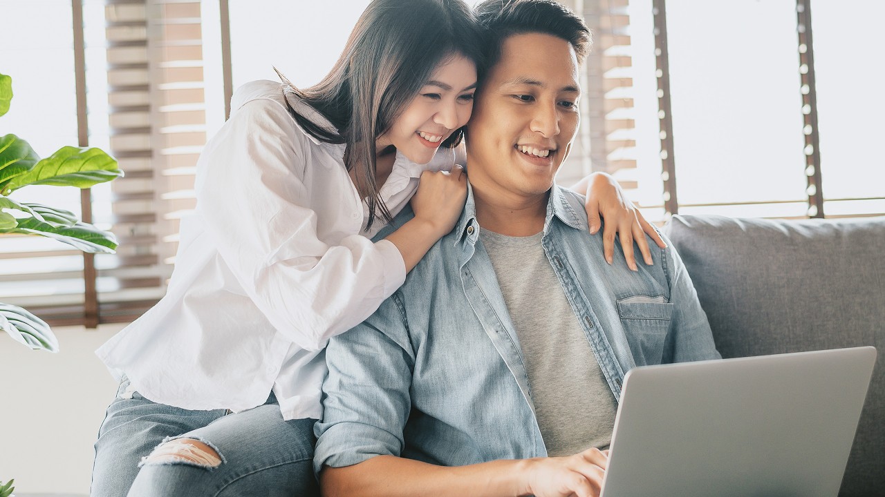 A young couple checking laptop on the sofa.