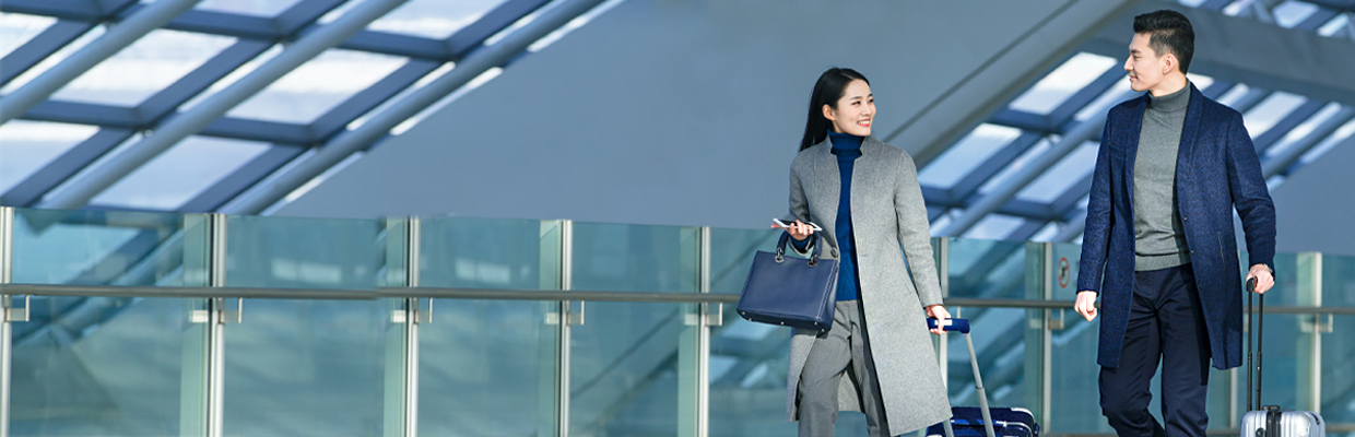 A young couple walking in airport with luggages; image used for HSBC Vietnam Mileage reward page.