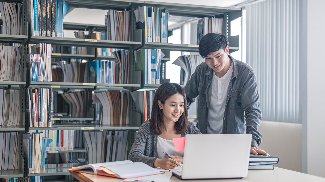 A young man and a young woman looking at a laptop in a library; image used for HSBC Vietnam overseas study page