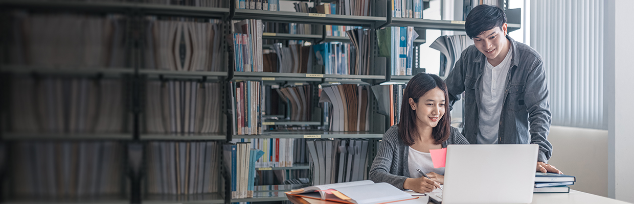 A young man and a young woman looking at a laptop in a library; image used for HSBC Vietnam overseas study page