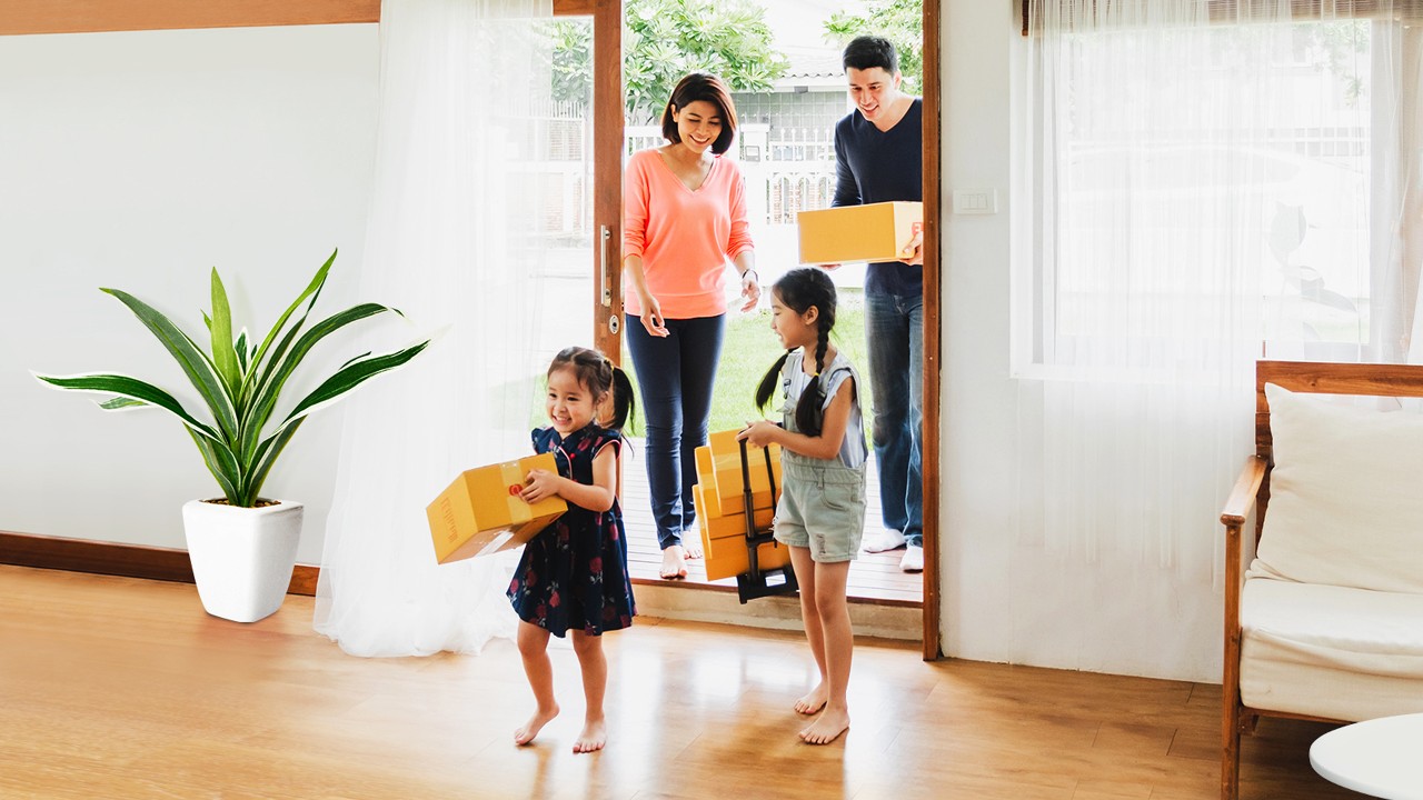 A family of four entering a house carrying some moving boxes; image used for HSBC Vietnam Home Mortgage Loan Page.