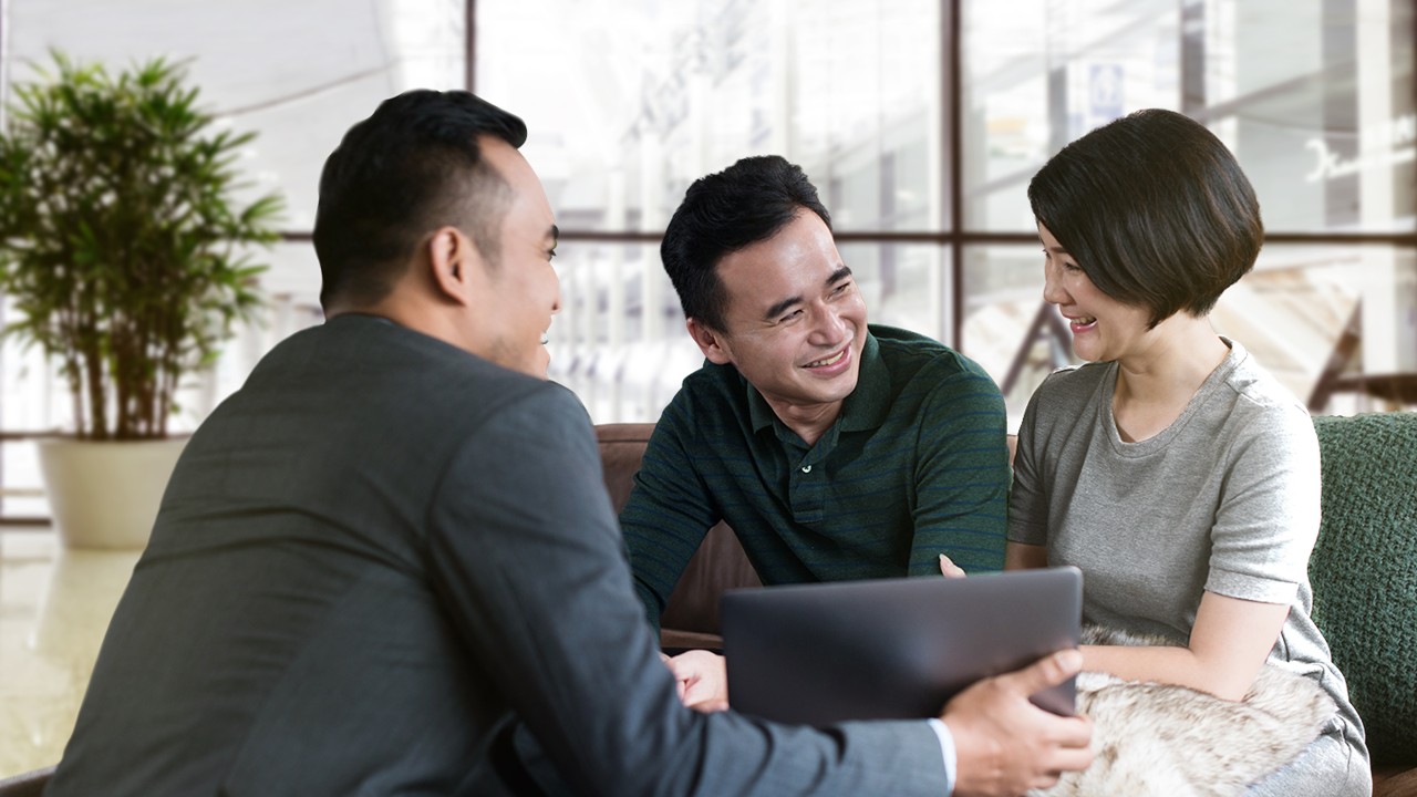 a happy smiling couple is using digital tablet with businessman; image used for HSBC Vietnam Green Loans page 