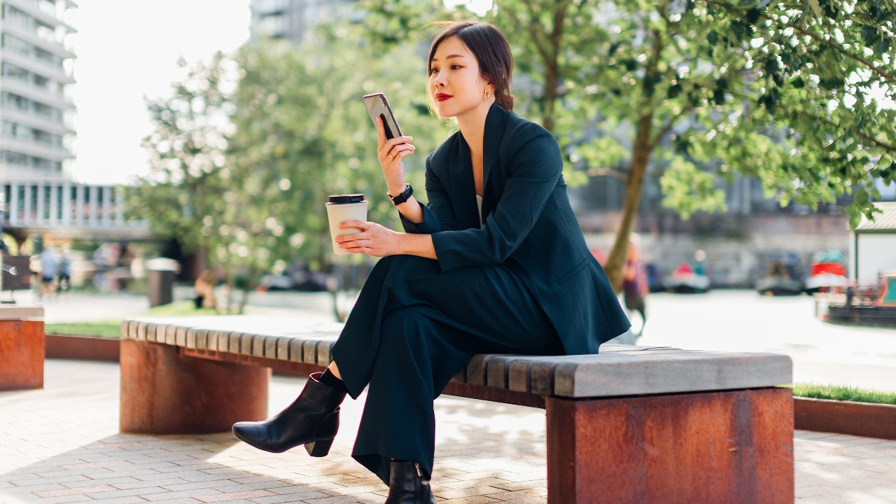 A woman sitting on a tree with a mobile phone in her hand; image used for HSBC Vietnam digital secure key page