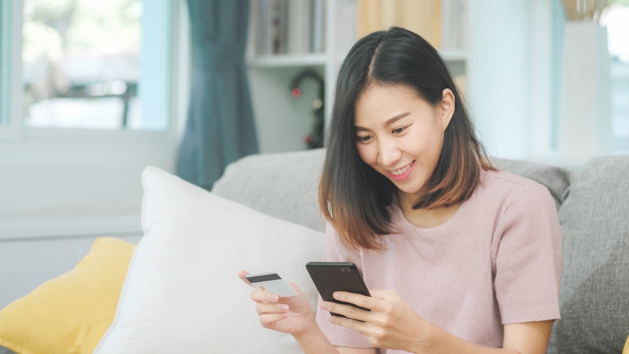 A young woman holding a mobile phone and a card; image used for HSBC Vietnam 3D Secure OTP page
