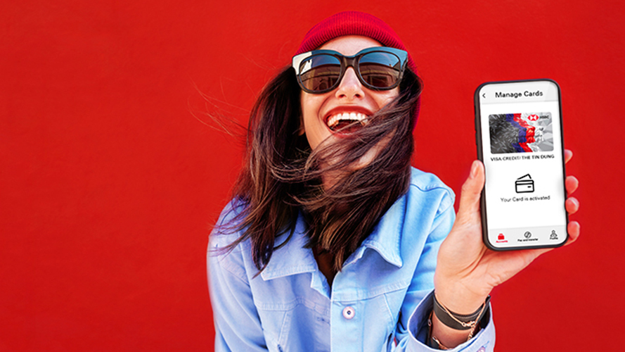 A young woman holding a mobile phone and a card; image used for HSBC Vietnam 3D Secure OTP page