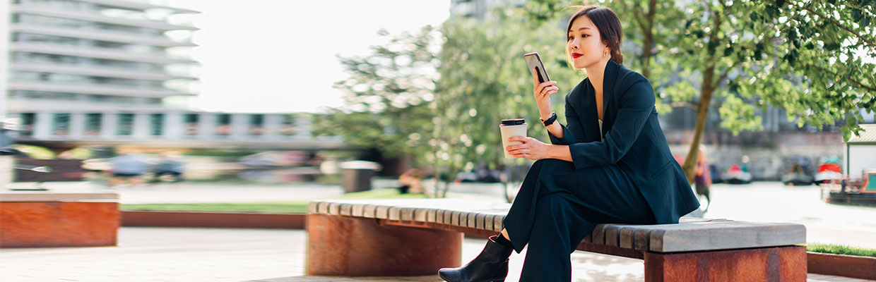 A woman sitting on a tree with a mobile phone in her hand; image used for HSBC Vietnam digital secure key page