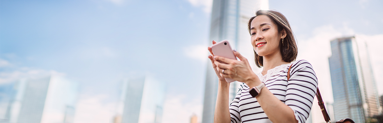 A female using mobile phone outside ; image used for HSBC Vietnam Mobile Banking page